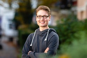 Nico Thies steht draussen in einem grauen Kapuzenpullover.