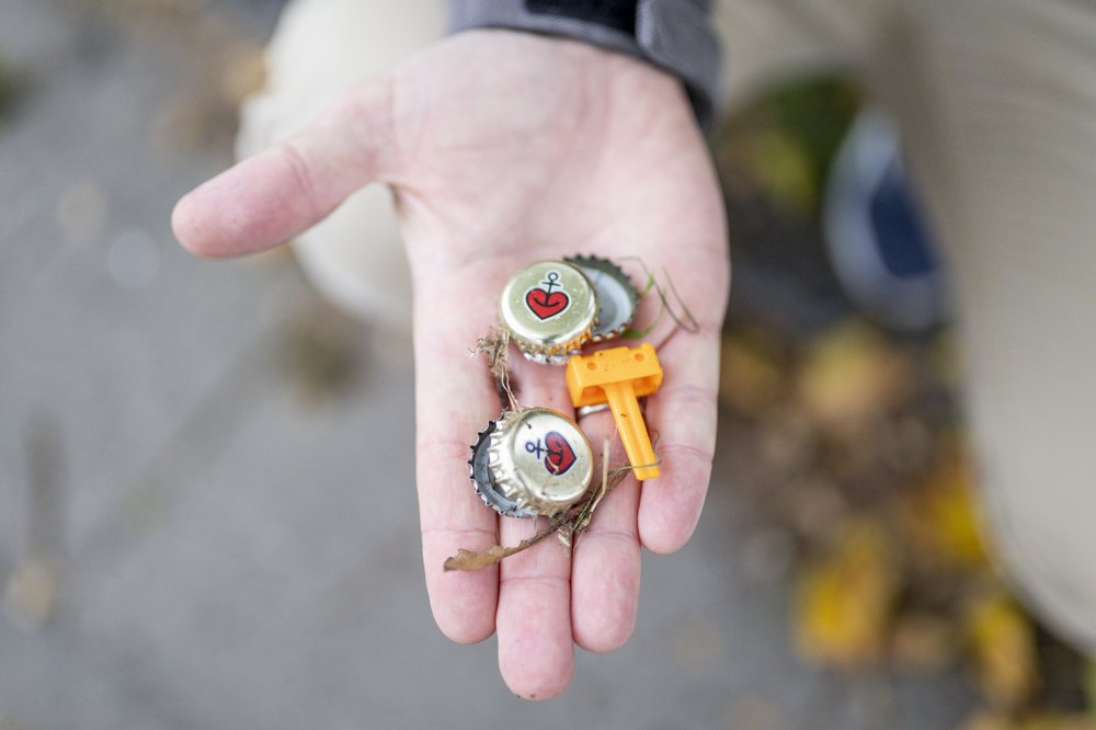 Unten: Ein Hand mit Müll: Flaschenverschlüsse und Plastik.